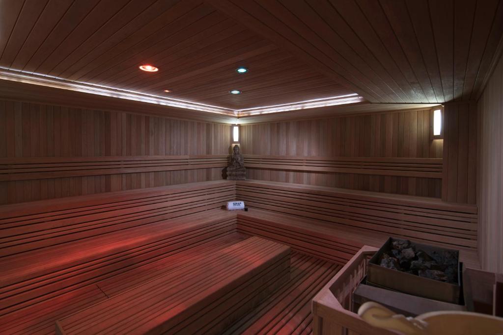 Mūsdienīga sauna ar koka iekārtojumu, kas ietver sēdvietas un akmeņus. Gaismas efekti rada relaksējošu atmosfēru.