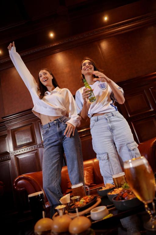 Divas sievietes bauda dzērienus un uzkodas Media Rotana bārā.