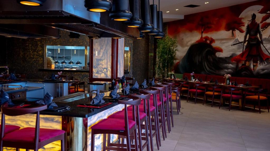 Mūsdienīgs restorāns Ali Baba Palace Resort ar sarkaniem krēsliem un māksliniecisku sienu gleznojumu.