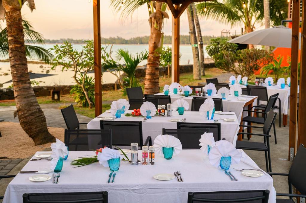 "Flowers of Paradise" restorāns pie jūras ar baltu galda klājumu.