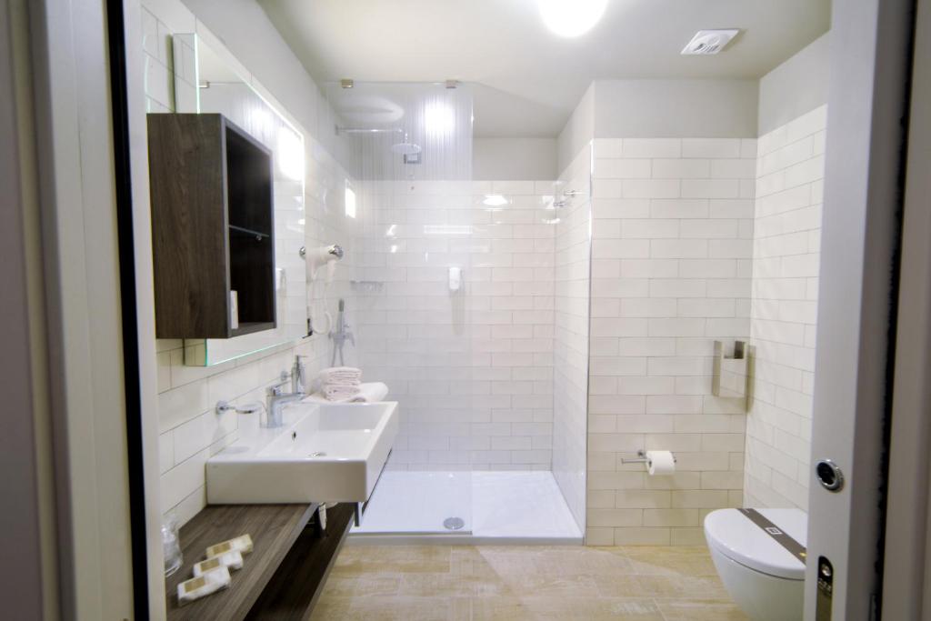 Mūsdienīgs vannaistaba ar stikla dušas kabīni, izlietni un koka skapīšiem, kas piepildīta ar gaišām flīzēm un dabīgām krāsām. Komfortabla un eleganta telpa.