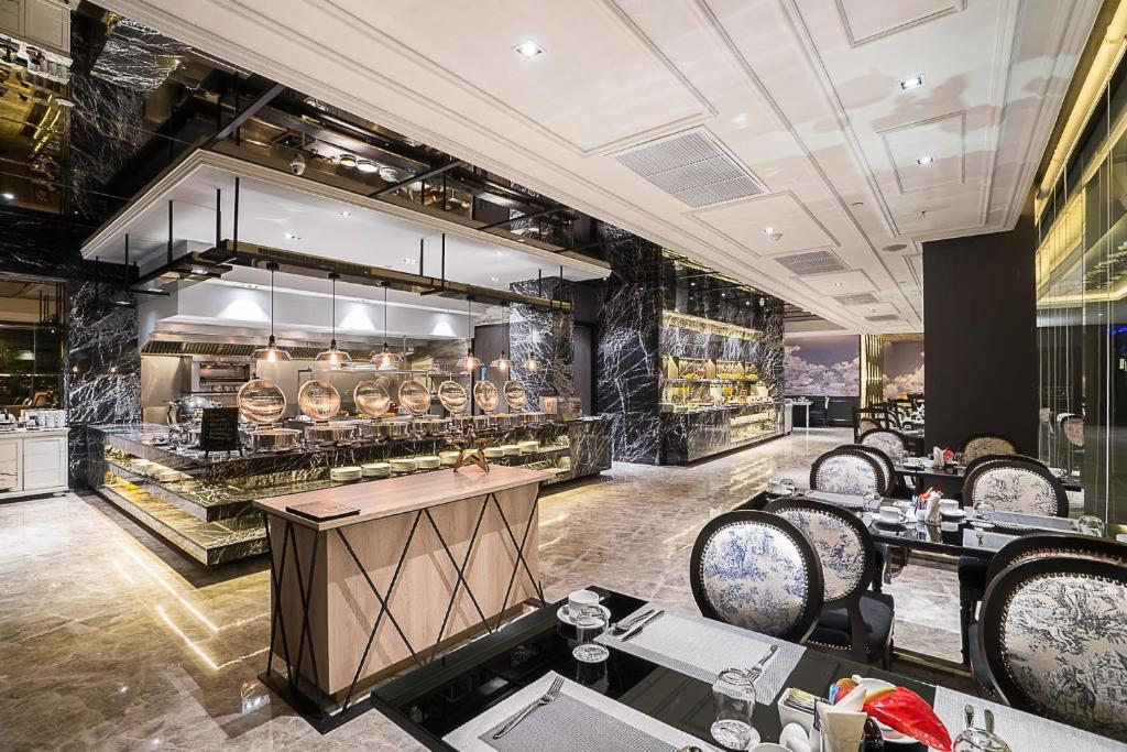 Elegants restorāns ar mūsdienīgu interjeru, kas ietver marmora sienas un moderna virtuves iekārtojumu. Gaismas apgaismojums un stilīgi galdi veido patīkamu atmosfēru.