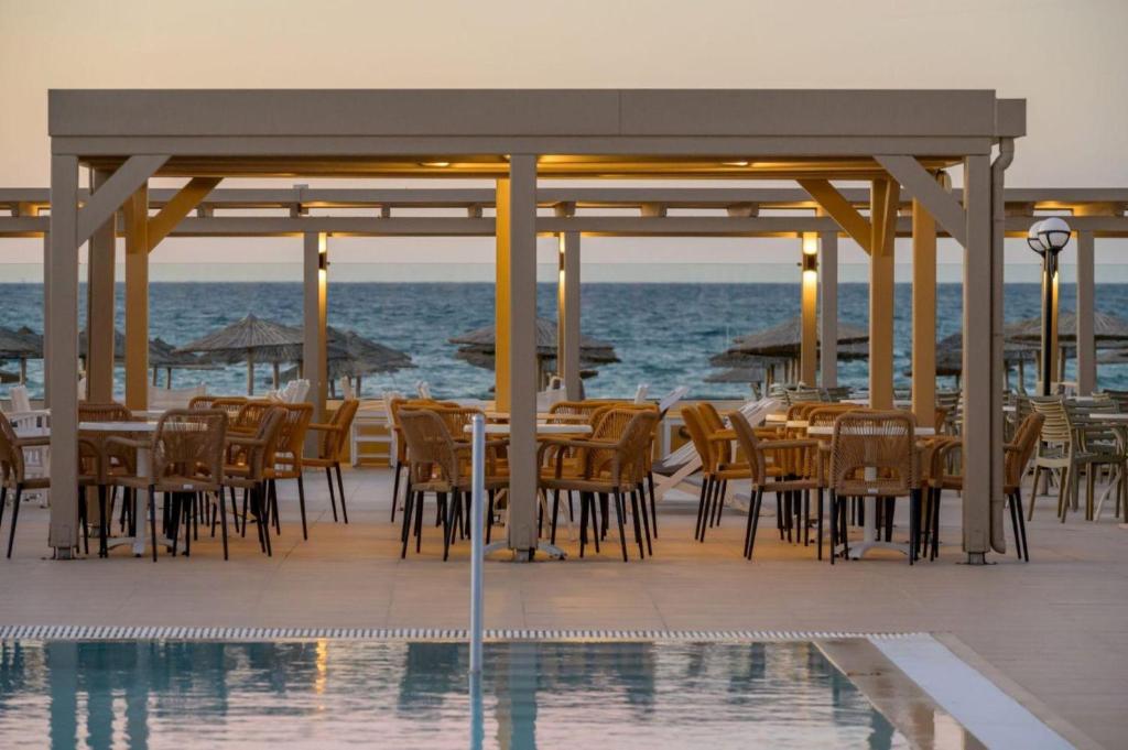 Neptuno Beach Resort terase ar krēsliem un galdiem pie ūdens.