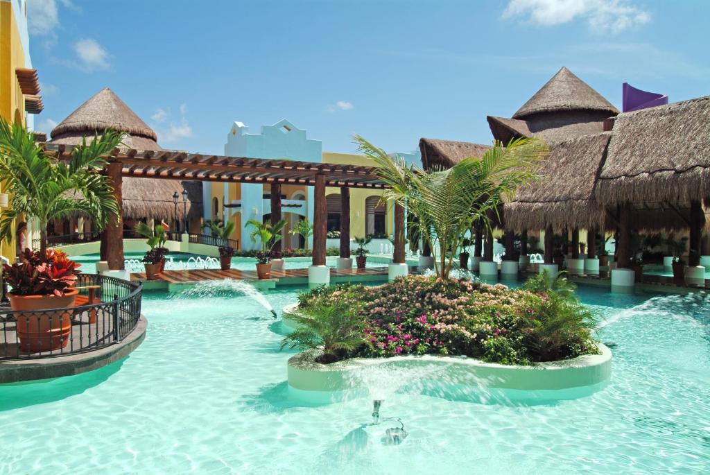 Vasaras kūrorta baseins ar tropu augiem un strūklakām, apkārt tradicionāla arhitektūra un saulaina debess. Ideāla vieta atpūtai un relaksācijai.