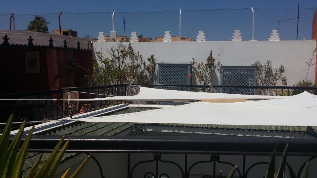 Terase ar balto audumu un zaļiem augiem, redzama zila debesis un arhitektūras elementi.