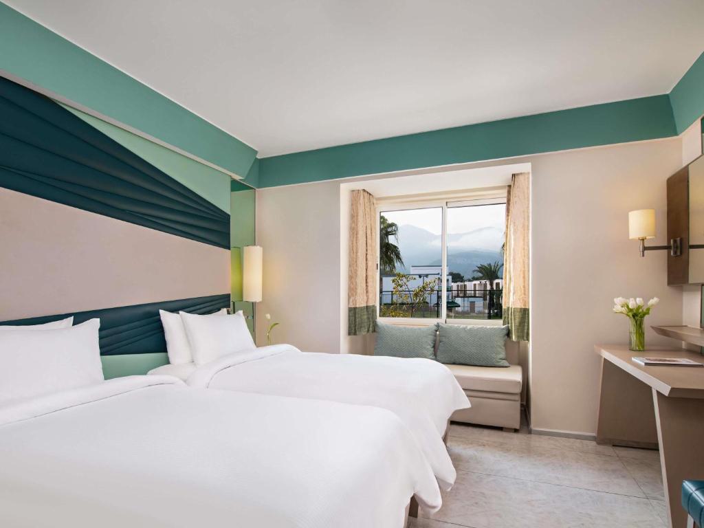 Numurs ar divām gultām Rixos Premium Tekirova ar skatu uz kalniem.