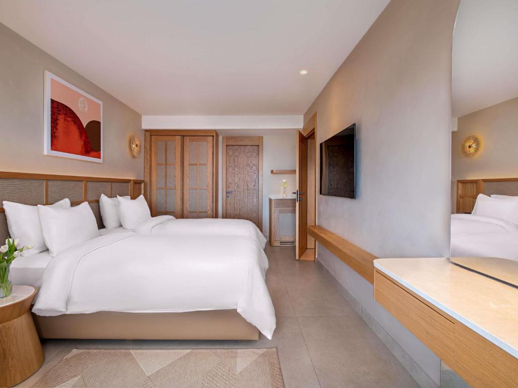 Mūsdienīgs divguļamais numurs Rixos Premium Tekirova ar televizoru un rakstāmgaldu.