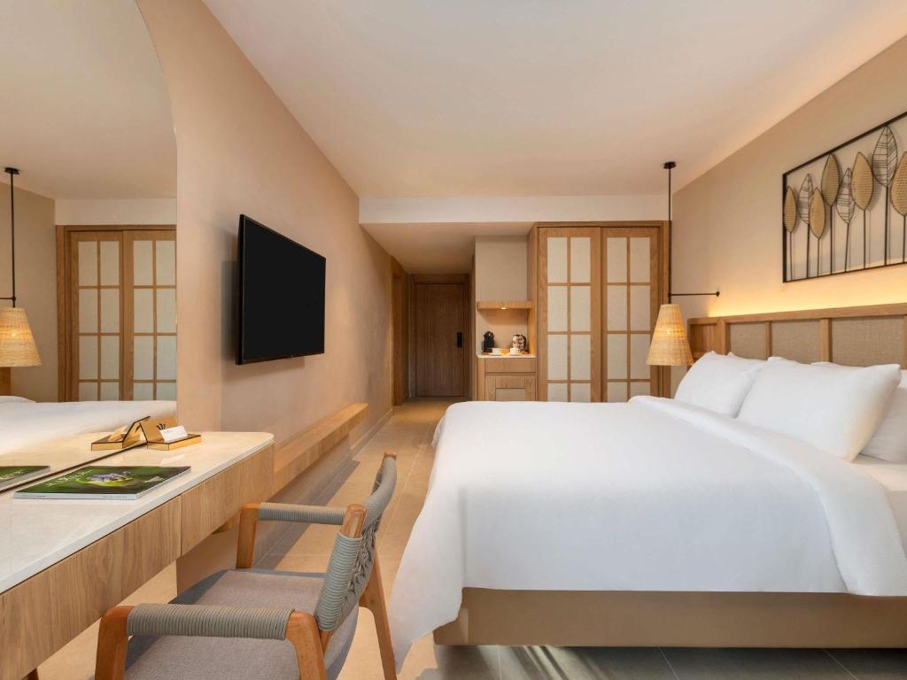 Mūsdienīgs numurs Rixos Premium Tekirova ar ērtu gultu un televizoru.