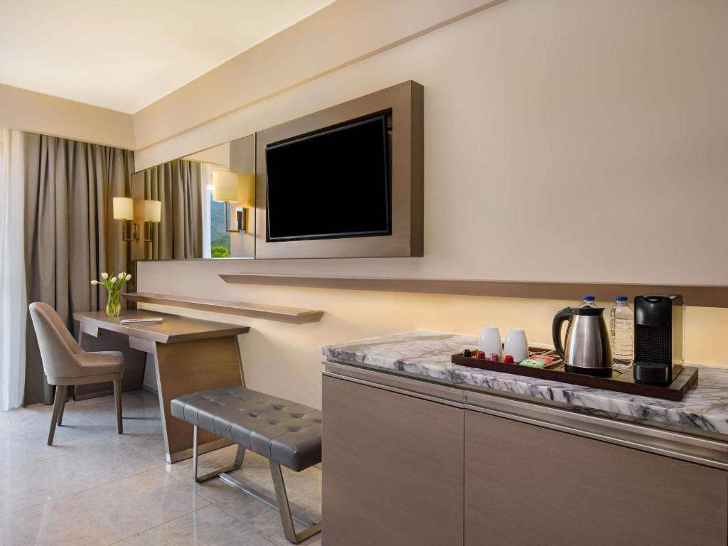 Mūsdienīgs numurs Rixos Premium Tekirova ar darba vietu un televizoru.