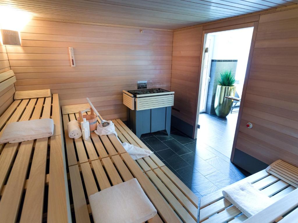 Mūsdienīga sauna ar koka plauktiem, siltuma avotu un relaksējošu atmosfēru. Telpā ir arī dekoratīvs augs un piekļuve ārējam telpam.