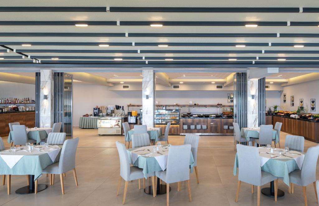 Restorāns Sea Coast Resort Halkidiki ar modernu interjeru un galdiem.