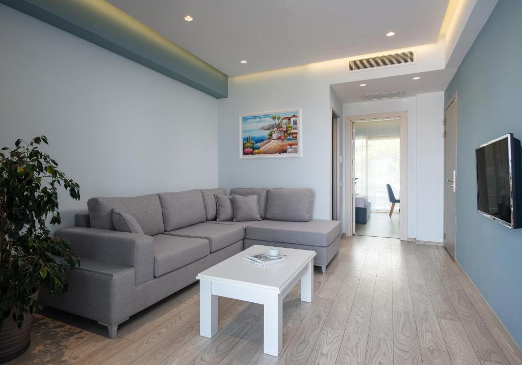 Mūsdienīgs viesnīcas numurs Sea Coast Resort Halkidiki ar dīvānu un TV.