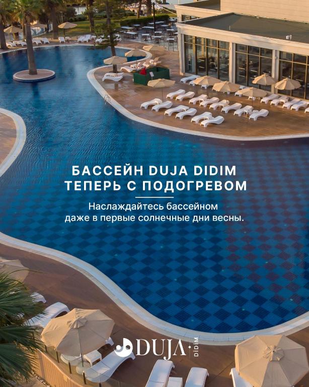 Siltais baseins Duja Didim ar sauļošanās krēsliem piekrastē