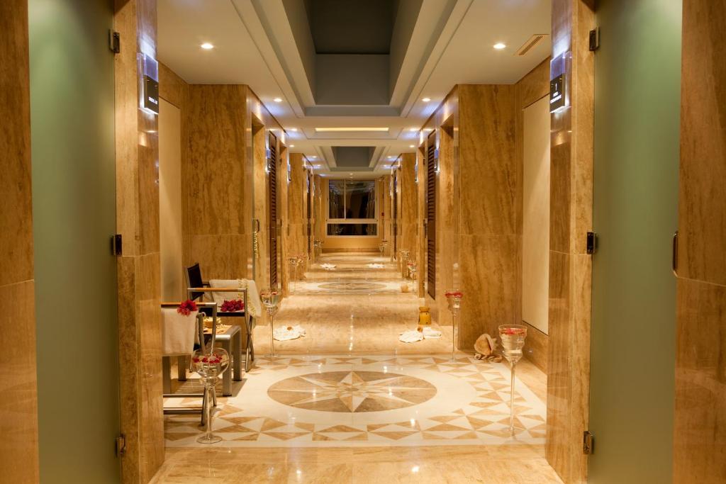 Eleganta viesnīcas halle ar marmora grīdu un modernu apgaismojumu, kas rada greznu atmosfēru. Redzamas dekorācijas un ziedi, kas piešķir siltumu un viesmīlību.
