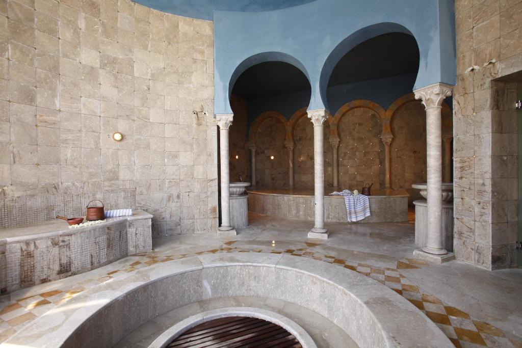 Eleganta pirts ar marmora sienām un arku kolonnām, radot relaksējošu atmosfēru. Telpā ir vairāki sēdvietas un ūdens avoti, kas veicina komfortu un labsajūtu.