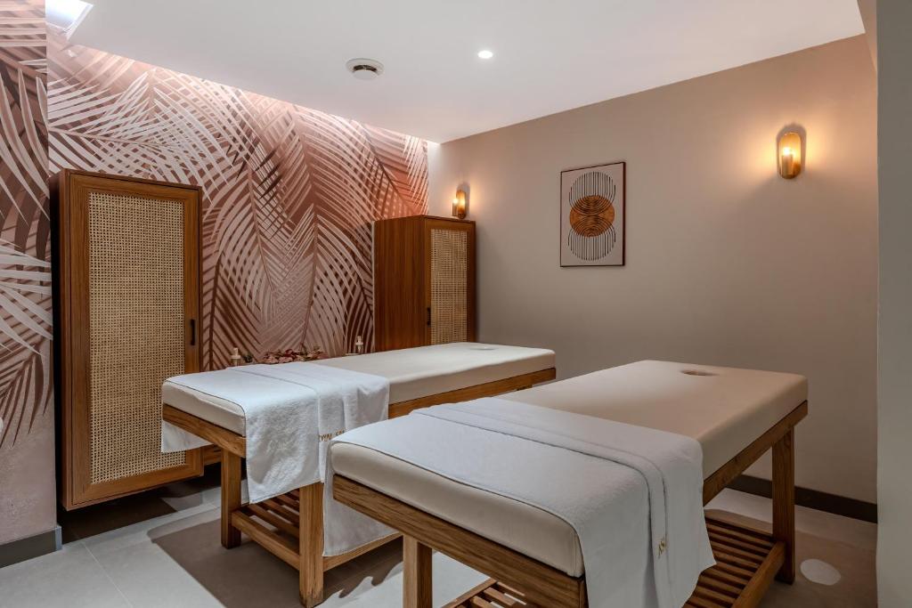 Masažu telpa Bergiz Hotels & Resort Kemer ar divām gultām un palmu motīvu sienu.