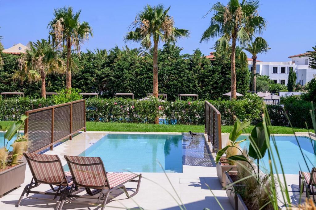 Zeus Hotels Ydoria Resort baseins ar palmām un atpūtas krēsliem