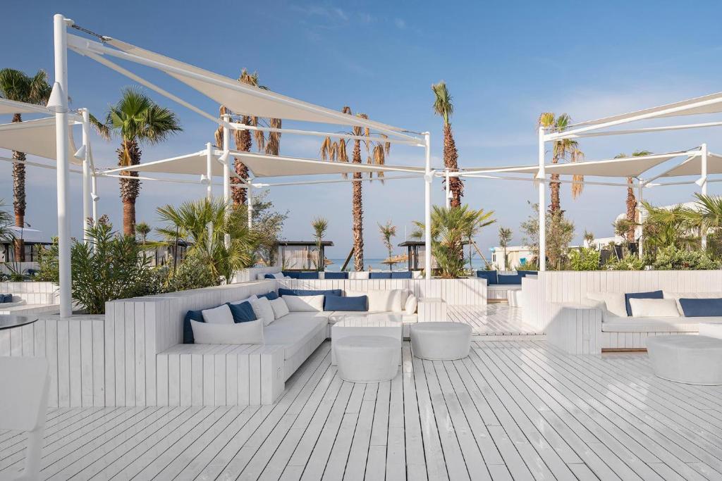Atpūtas zona piekrastē pie Voyage Belek Golf & Spa ar baltām mēbelēm un palmām.