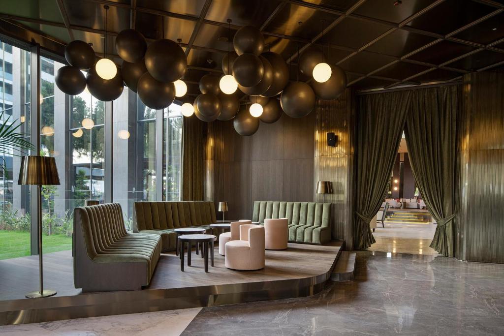 Moderns viesnīcas vestibils ar elegantiem dīvāniem un dekoratīvām lampām Voyage Belek Golf & Spa.