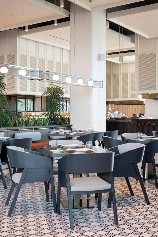 Moderns restorāns Voyage Belek Golf & Spa ar elegantiem galdiem un krēsliem.
