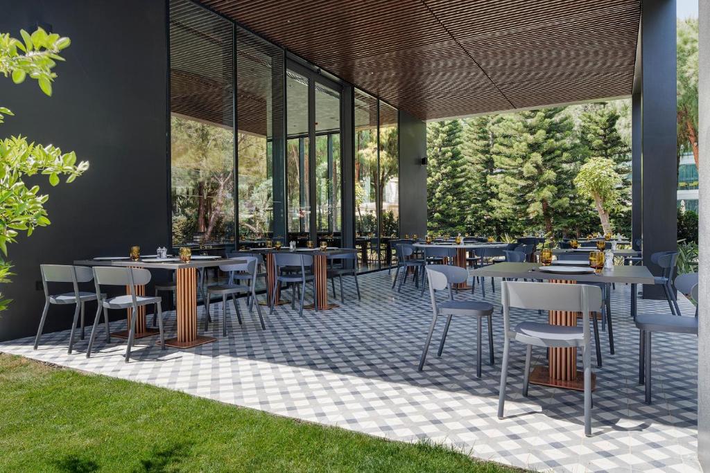 Moderns āra restorāns pie Voyage Belek Golf & Spa ar elegantiem galdiem un krēsliem.