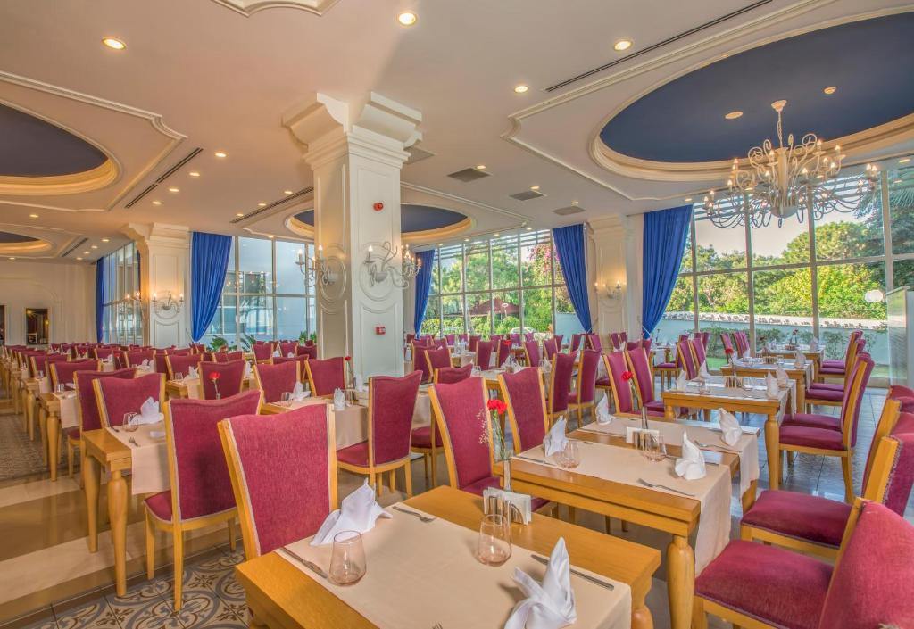 Eleganta restorāna iekārtojums Sherwood Exclusive Kemer ar sarkaniem krēsliem.