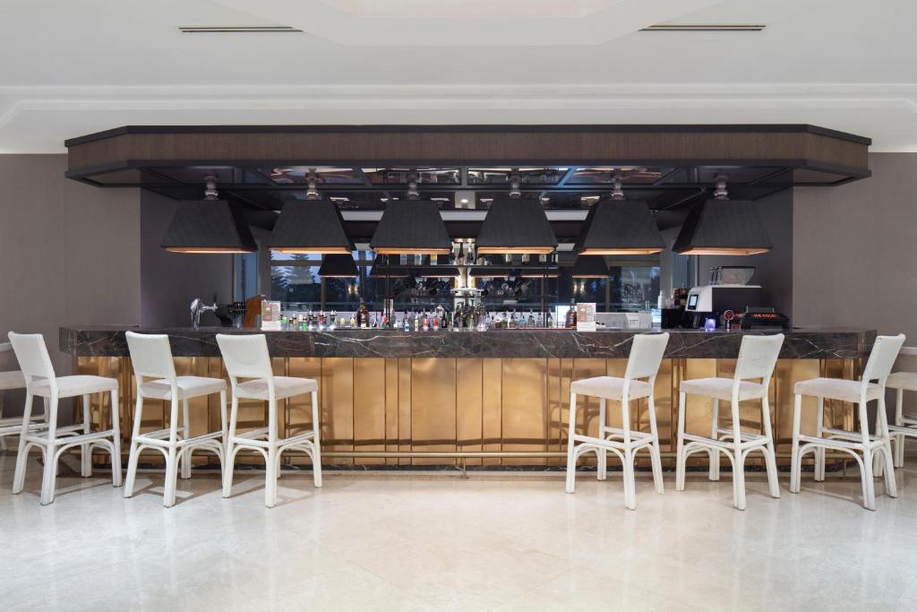 Elegants bārs Mirage Park Resort ar stilīgām krēslām un izgaismotu letīti.