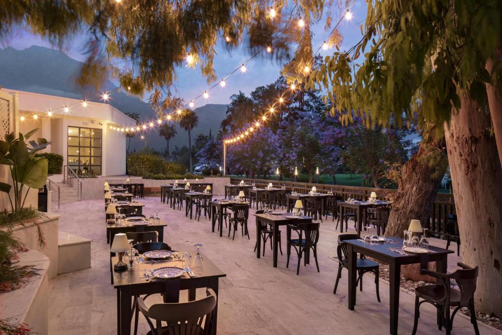 Āra restorāns Mirage Park Resort ar lampiņām un galdiem piekrastē