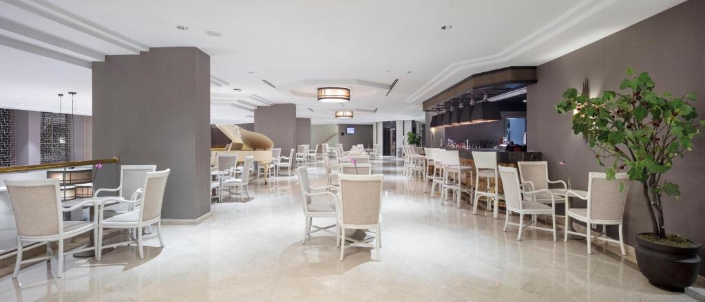 Mirage Park Resort elegantā bāra zona ar baltiem krēsliem un viesmīlīgu atmosfēru