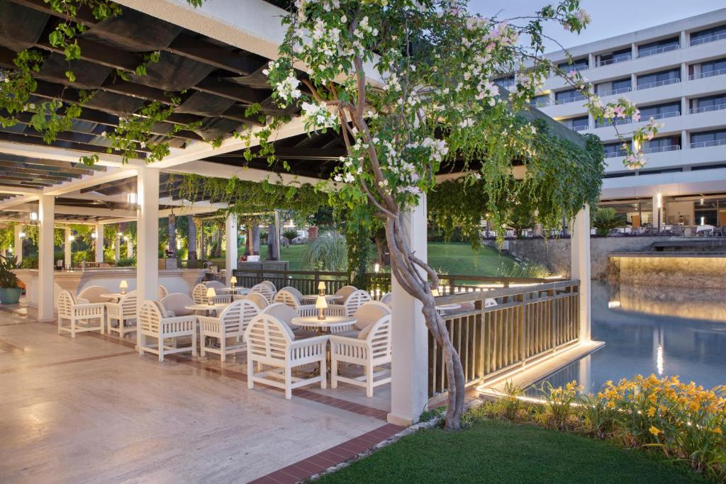 Mirage Park Resort āra terase ar galdiem un zaļumiem pie ūdens