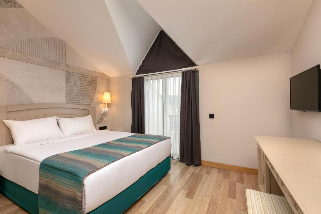 Moderns numurs viesnīcā Greenwood Kemer Resort ar balkonu un televizoru.