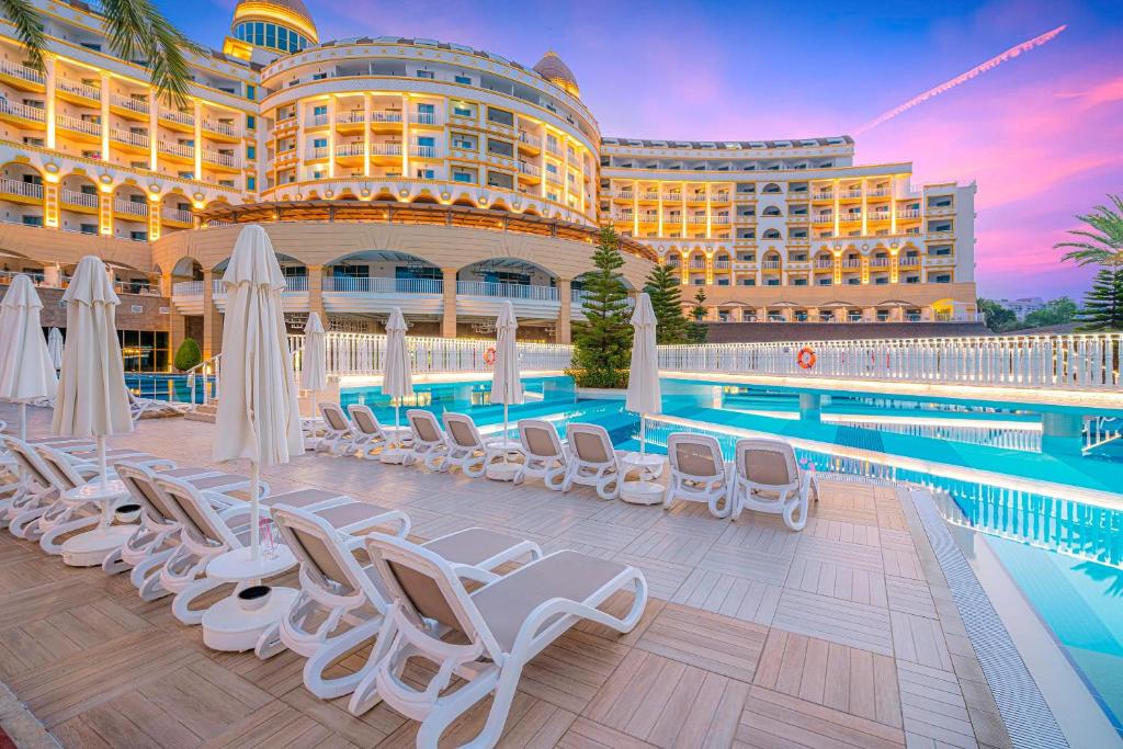 Kirman Sidemarin Beach & Spa baseins ar sauļošanās krēsliem un zilo debesu fonu.