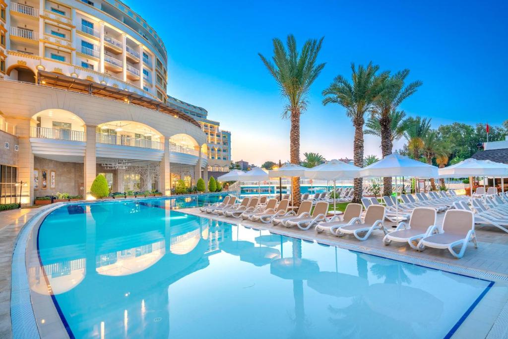 Kirman Sidemarin Beach & Spa baseins ar palmu kokiem un sauļošanās krēsliem