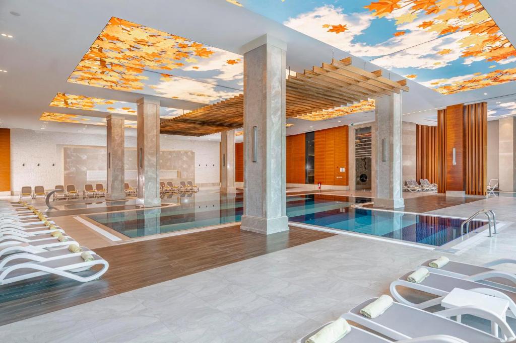 Luksusa iekštelpu baseins Kirman Sidemarin Beach & Spa ar dzeltenām lapām uz griestiem.