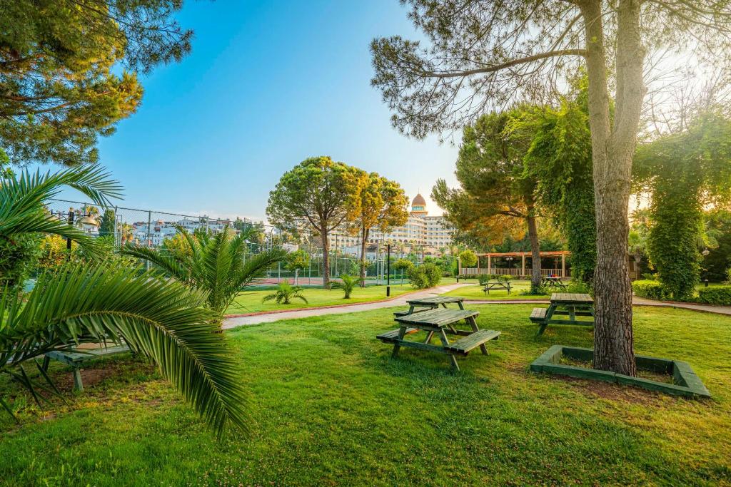 Zaļais parks pie Kirman Sidemarin Beach & Spa ar galdiem un kokiem.