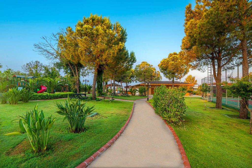 Skaists parks pie Kirman Sidemarin Beach & Spa ar zaļiem stādiem un takām.