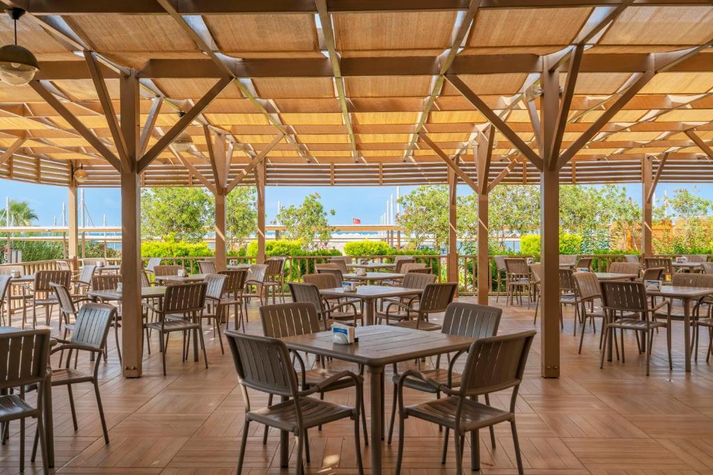 Restorāna terase piekrastē ar koka galdiem un krēsliem Kirman Sidemarin Beach & Spa