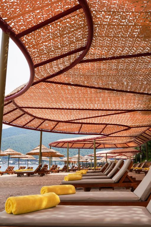 Atpūtas krēsli pie pludmales La Blanche Island Bodrum, saules segumi.