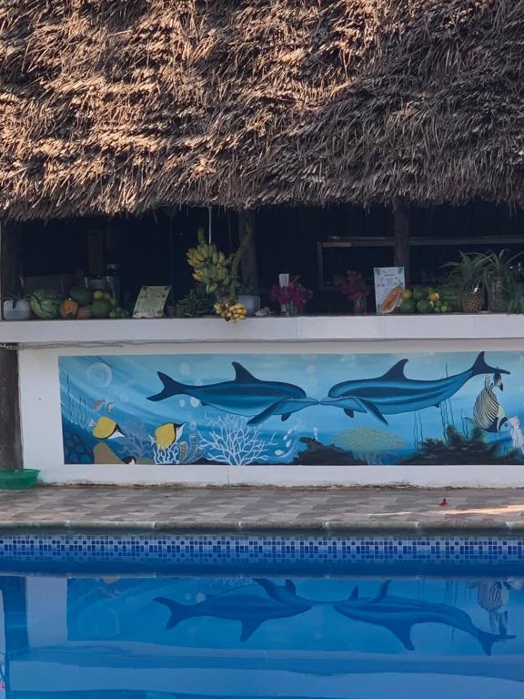 Bārs pie baseina ar delfīnu gleznojumu Isla Bonita Zanzibar Beach Resort