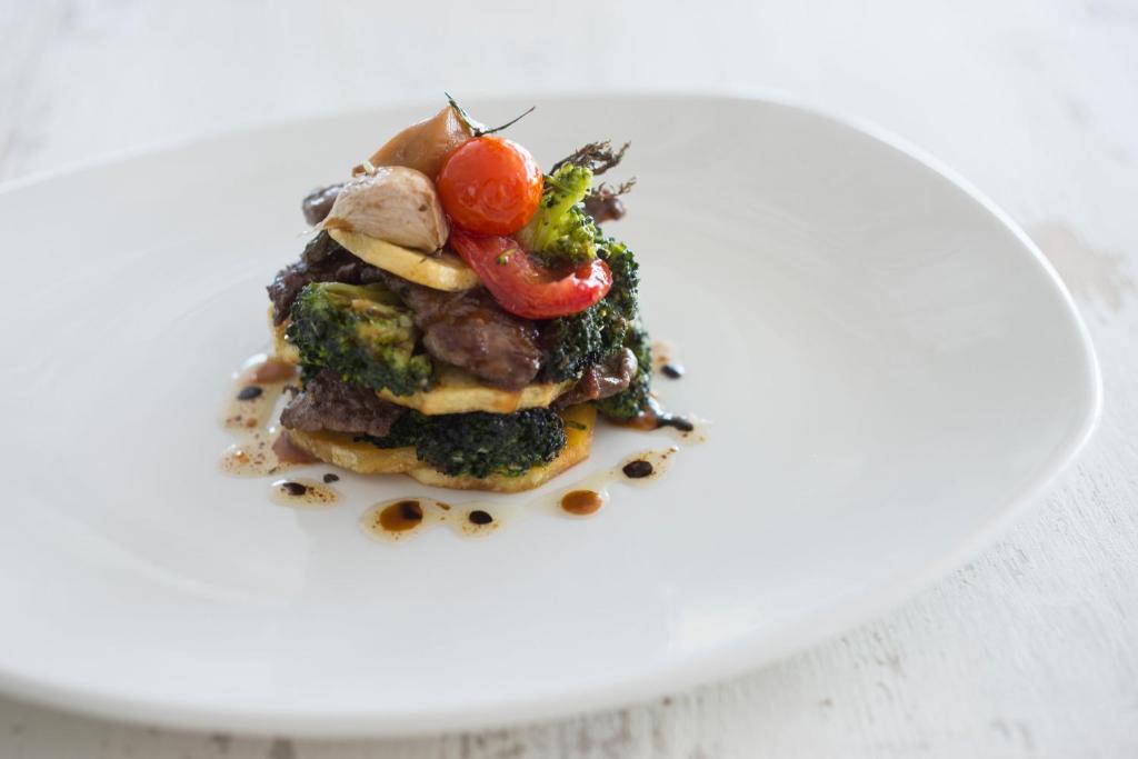 Skaista un eleganta maltīte ar gaļu, brokoļiem un dārzeņiem, pasniegta uz baltā šķīvja.