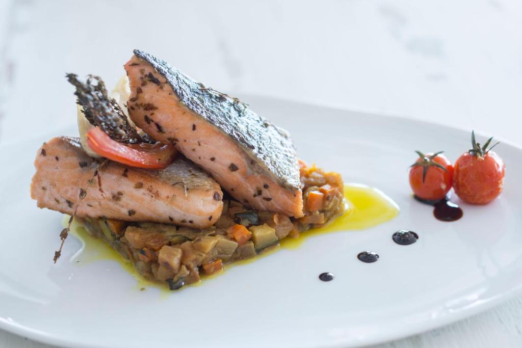 Grilēta laša fileja ar dārzeņu biezeni, dekorēta ar tomātiem un garšaugiem. Ideāla maltīte veselīgām vakariņām.