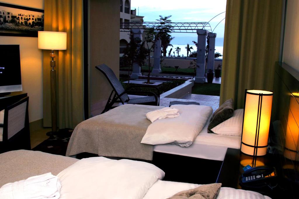 Mūsdienīgs viesnīcas numurs ar divām gultām, dīvānu un televizoru, kas sniedz skatu uz dārzu un jūru. Telpa ir apgaismota ar mūsdienīgu lampu un ir iekārtota ar patīkamām krāsām.