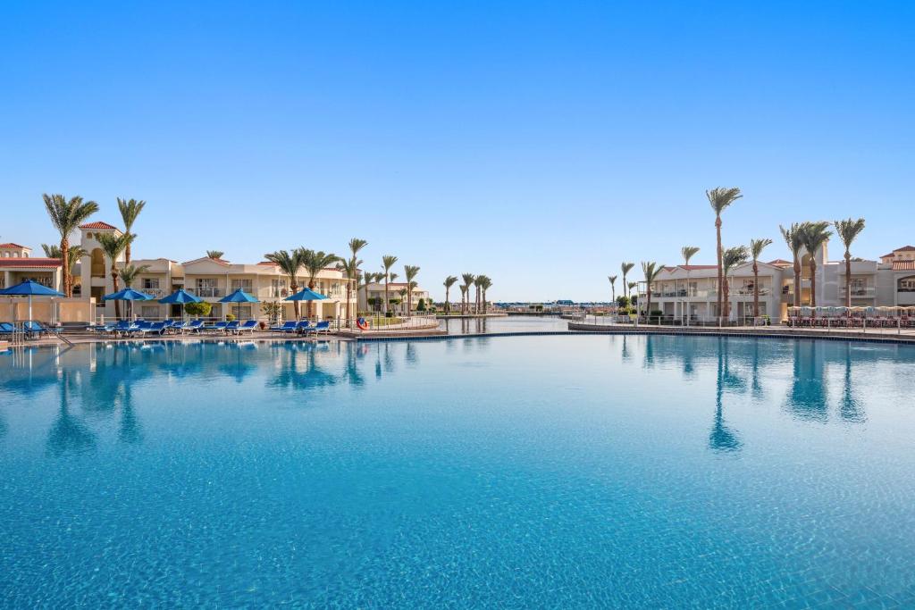 Pickalbatros Dana Beach Resort baseins piekrastē ar palmām un saulessargiem