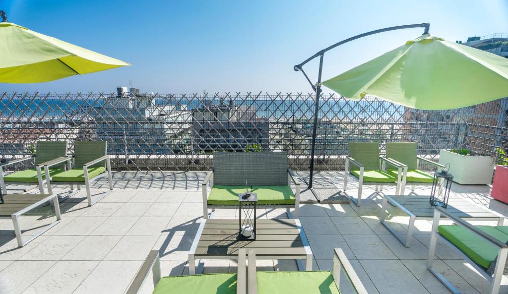 Saulaina terase ar zaļām saulessargiem un ērtām mēbelēm, nodrošinot lielisku skatu uz pilsētu un jūru. Ideāli piemērota atpūtai un relaksācijai.