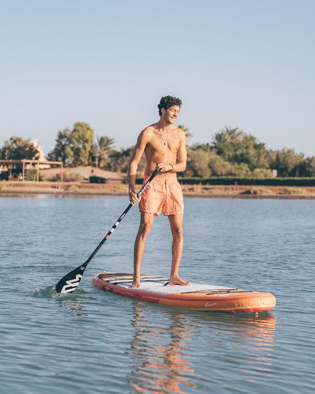 Vīrietis, kas stāv uz SUP dēļa piekrastē, Cook's Club El Gouna.