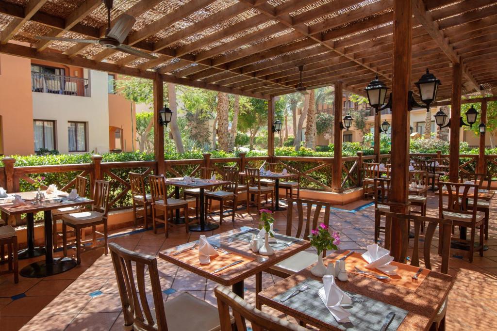 Āra restorāns pie Jaz Makadi Saraya Resort ar galdiem un ziediem.