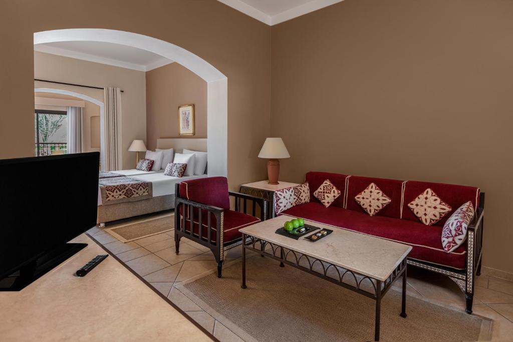 Numurs viesnīcā Jaz Makadi Saraya Resort ar ērtu dīvānu un televizoru.