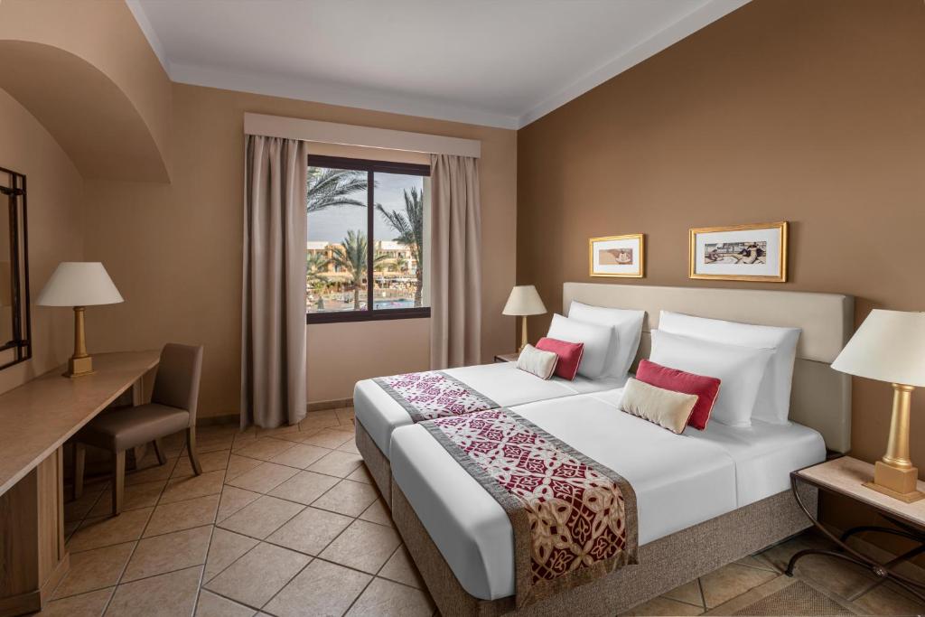 Jaz Makadi Saraya Resort numurs ar divām gultām un skatu uz dārzu.