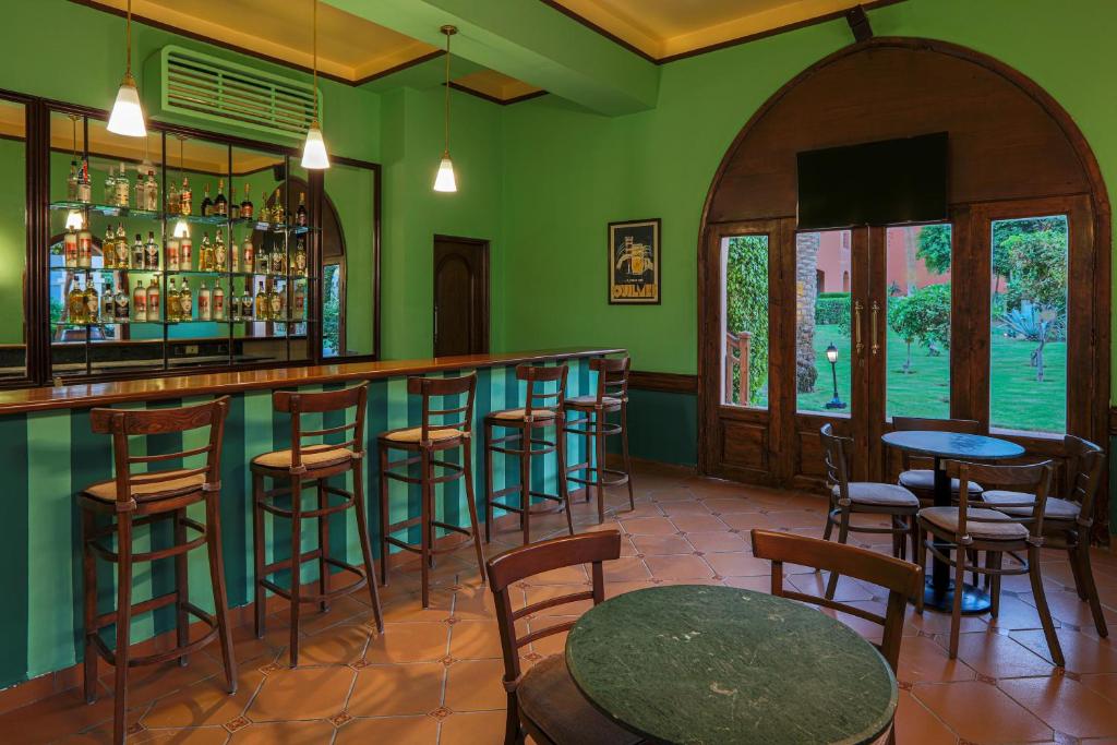 Bārs ar zaļām sienām un koka mēbelēm hotelī Jaz Makadi Saraya Resort.