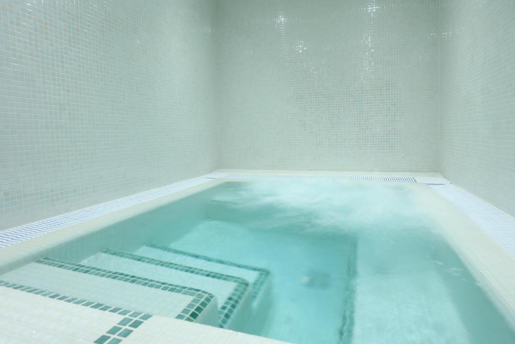 Mūsdienīgs un elegants spa baseins ar burbuļiem, kas atrodas apmūrēts ar gaišām mozaīkas flīzēm. Ideāla vieta relaksācijai un atpūtai.